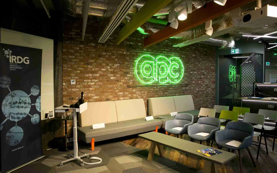 The APC innovation centre in Dublin — an open presentation space with APC's illuminated sign on the wall.